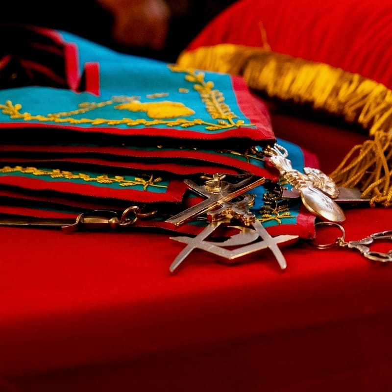 Mandiles y joyas de los oficiales de la Logia, apilados sobre terciopelo rojo.